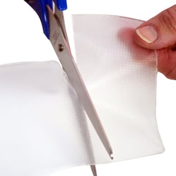 Clear Gel Mate™ silicone gel sheet being trimmed with scissors for a customized fit over a scar.