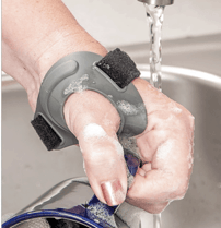 Hand washing a dish while wearing the waterproof CMCcare Thumb Brace, demonstrating support and stabilization of the CMC joint during everyday activities.